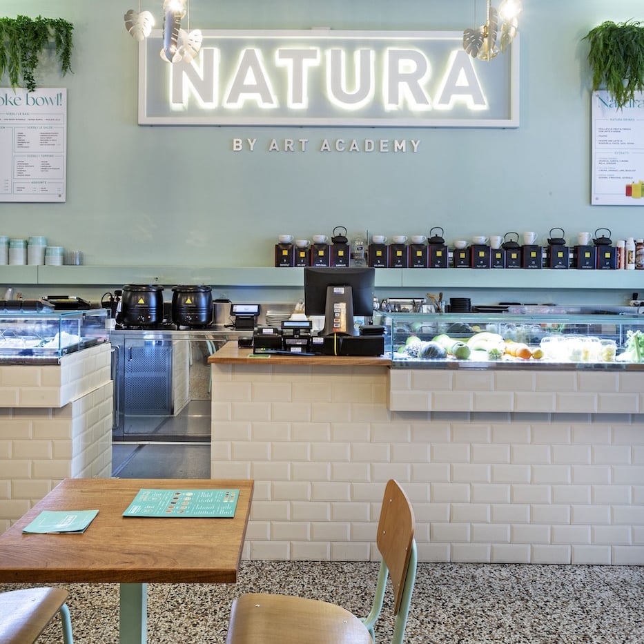 interno del locale Natura, con un'insegna al neon, banchi frigo rivestiti in piastrelle e pareti color pastello